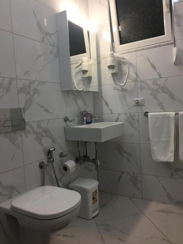 a bathroom with a toilet and a sink and a mirror at Villa Orkidea in Sarandë