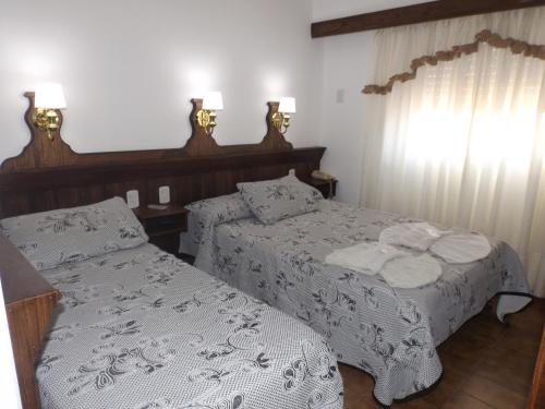a bedroom with two beds with white sheets at Hotel Alemán in Gualeguaychú