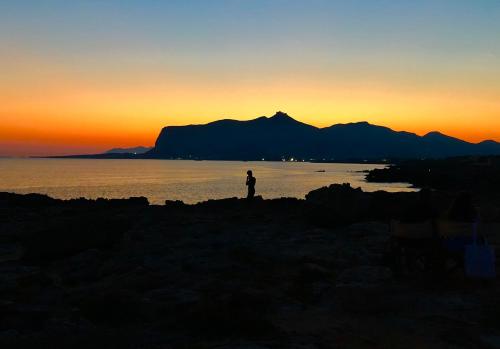 a person standing on the edge of the water at sunset at La Casa del Limoneto in Favignana