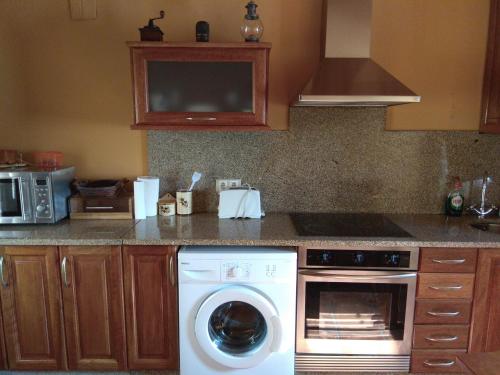 cocina con lavadora y microondas en Casa Ruso, en Os Muinos