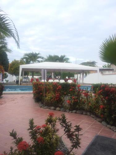 a pavilion by a swimming pool with flowers in a courtyard at Hotel Kemarios in Tonsupa
