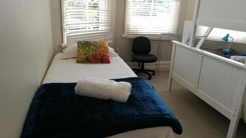a bedroom with a bed with a pillow and a chair at Regent Residential Villa in Whangarei