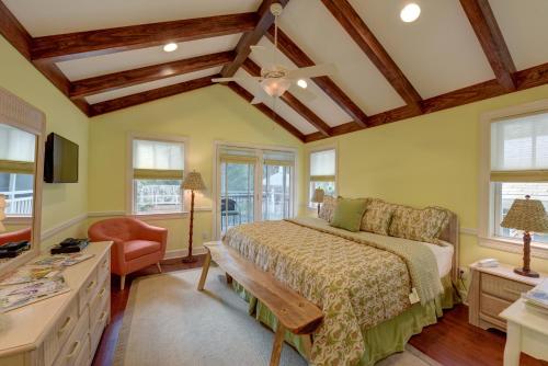 a bedroom with a bed and a chair and windows at The Grey Owl Inn in Saint Simons Island