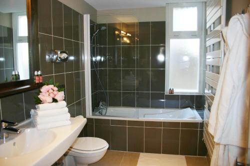 a bathroom with a tub and a toilet and a sink at Hotel Bellevue in Amboise