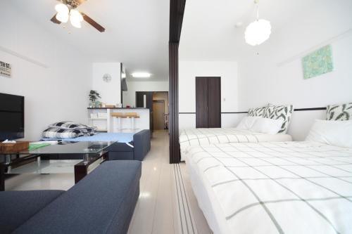 1 Schlafzimmer mit 2 Betten, einem Tisch und einem Sofa in der Unterkunft EX Itoman Apartment 802 in Itoman