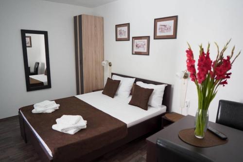 a bedroom with a bed and a table with a vase of flowers at Apartments & Dream Rooms in Niš