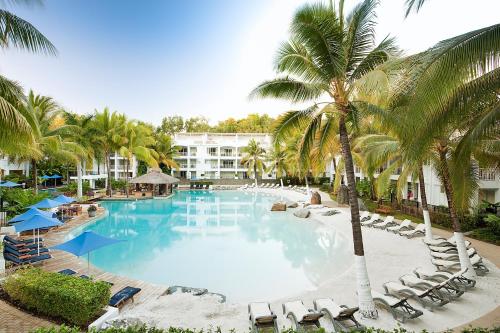 a large swimming pool with chairs and palm trees at Palm Cove Paradise - Couples spa beach getaway in Palm Cove