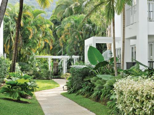 a walkway in front of a building with palm trees at Palm Cove Paradise - Couples spa beach getaway in Palm Cove