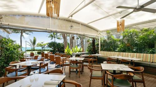 a restaurant with tables and chairs and a view of the ocean at Palm Cove Paradise - Couples spa beach getaway in Palm Cove
