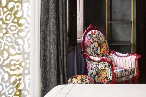 a red chair with a painting on it next to a window at Dar Kandi in Marrakech