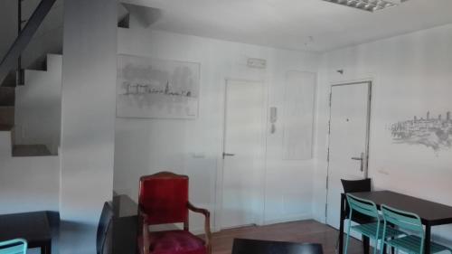 a room with a table and a red chair at TOLETUM low cost LOFTS diáfanos o 2dormitorios PARKING Municipal Gratis al aire libre a 100m in Toledo
