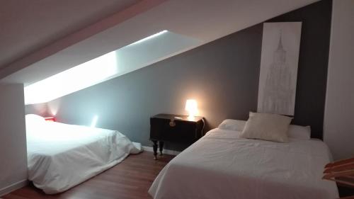 a bedroom with two beds and a light on the wall at TOLETUM low cost LOFTS diáfanos o 2dormitorios PARKING Municipal Gratis al aire libre a 100m in Toledo