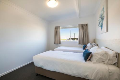 a white bedroom with a bed and a window at Nightcap at Golden Beach Tavern in Caloundra