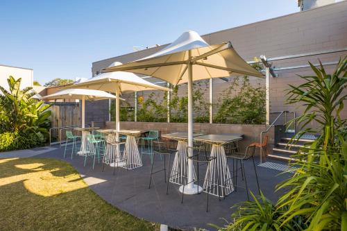 a patio area with umbrellas and chairs at Nightcap at Golden Beach Tavern in Caloundra