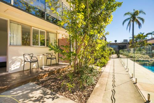 a patio with two chairs and a tree in front of a building at Nightcap at Golden Beach Tavern in Caloundra