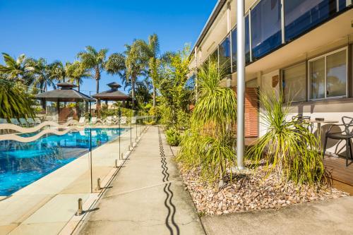 a house with a swimming pool and palm trees at Nightcap at Golden Beach Tavern in Caloundra
