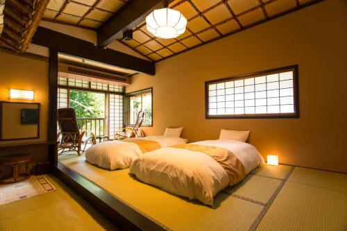 1 dormitorio con 2 camas, TV y ventanas en Honke Bankyu, en Nikko