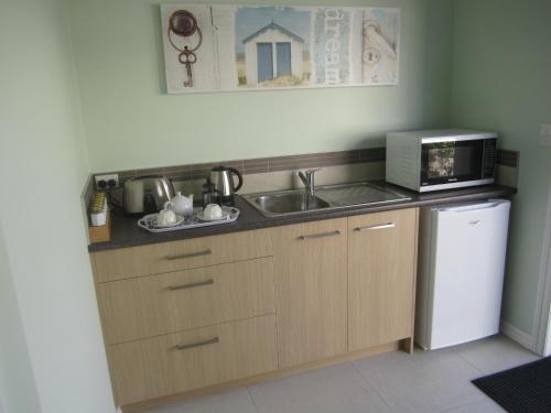 a kitchen with a sink and a microwave at Hyecroft Lodge in Whangarei