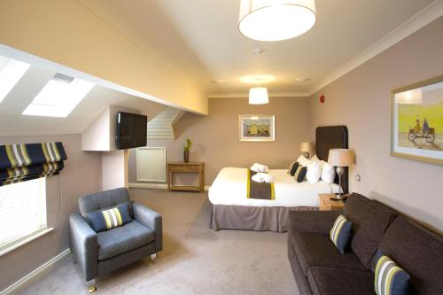 a bedroom with a bed and a chair and a couch at Breckland Lodge in Attleborough