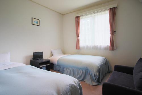 a hotel room with two beds and a window at Pension Aroma Herbs Le Lagon in Yamanakako