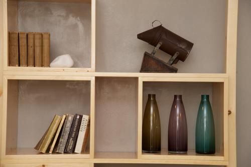 a wooden shelf with vases and books on it at G.Living 365 in Ayia Evfimia