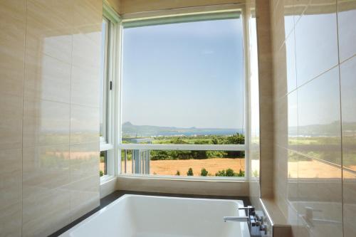 a bath tub in a bathroom with a large window at Coral B&B in Hengchun