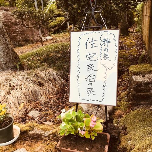 a sign that is sitting next to some plants at Kizuna no Ie in Uozu