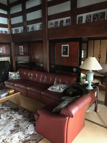 a living room with a leather couch and a lamp at Kizuna no Ie in Uozu
