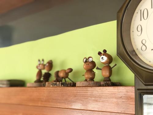 a group of figurines on a shelf next to a clock at Fureai No Yado Yasuragi in Nozawa Onsen