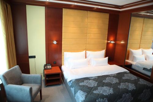 a hotel room with a bed and a chair at Garni Hotel Aleksandar in Novi Sad