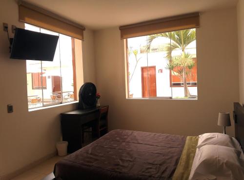 a bedroom with a bed and a window with a television at Caballito de Totora in Huanchaco