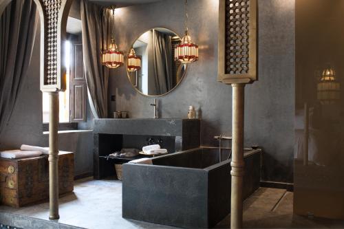 a bathroom with a black tub and a mirror at Dar Kandi in Marrakech