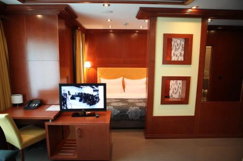 a room with a bed and a desk with a computer at Garni Hotel Aleksandar in Novi Sad