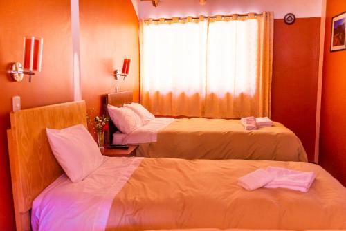 a hotel room with two beds and a window at Peru Quechua's Lodge Ollantaytambo in Ollantaytambo