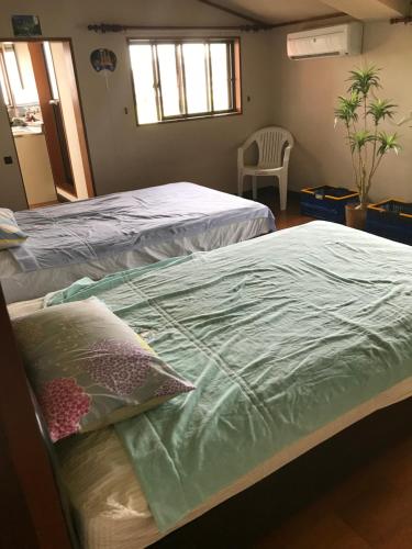 a bedroom with two beds and a chair at Kizuna no Ie in Uozu