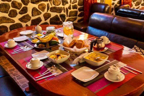 a wooden table with food and drinks on it at Peru Quechua's Lodge Ollantaytambo in Ollantaytambo