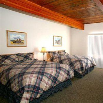 a bedroom with two beds and a wooden ceiling at Trails End Motel Sheridan in Sheridan