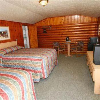 a hotel room with two beds and a table and a television at Trails End Motel Sheridan in Sheridan