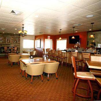 a restaurant with tables and chairs and a bar at Trails End Motel Sheridan in Sheridan