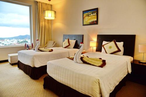 um quarto de hotel com três camas e uma grande janela em Sai Gon Ban Me Hotel em Buon Ma Thuot