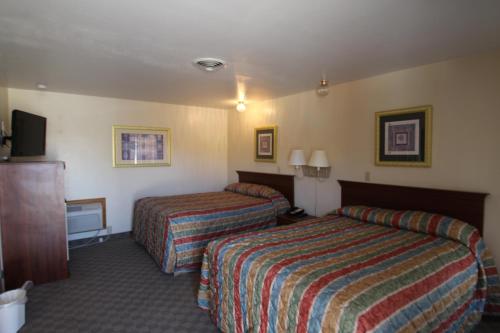 a hotel room with two beds and a flat screen tv at Trails End Motel Sheridan in Sheridan