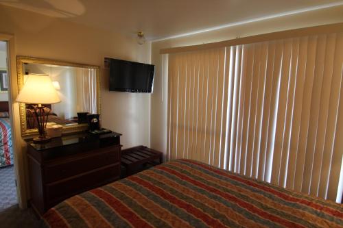 a hotel room with a bed and a dresser and a mirror at Trails End Motel Sheridan in Sheridan