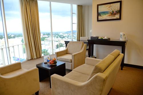 a living room with chairs and a table and windows at Sai Gon Ban Me Hotel in Buon Ma Thuot