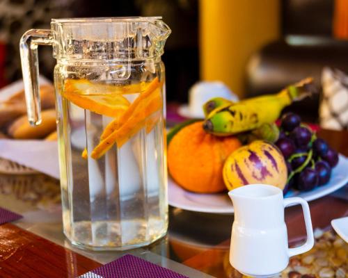 a jug of water with oranges and fruit on a table at Peru Quechua's Lodge Ollantaytambo in Ollantaytambo