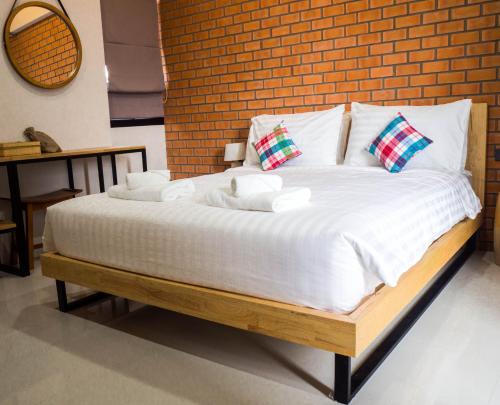 a bed with white sheets and pillows in front of a brick wall at Luck Esan Loft in Ubon Ratchathani