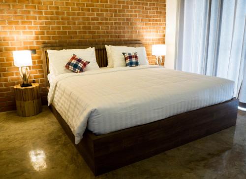 a bedroom with a large bed with a brick wall at Luck Esan Loft in Ubon Ratchathani