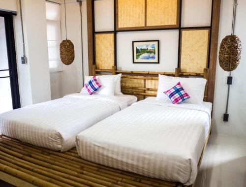 two beds sitting next to each other in a room at Luck Esan Loft in Ubon Ratchathani