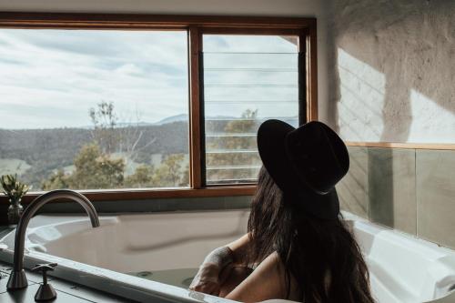 a woman sitting in a bath tub looking out a window at Kangaroo Ridge Retreat in Healesville