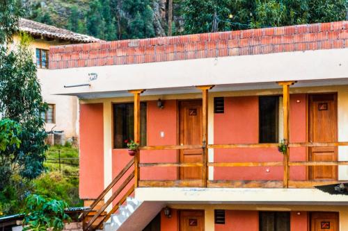 a house with a red facade and a balcony at Peru Quechua's Lodge Ollantaytambo in Ollantaytambo