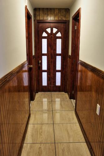 an empty hallway with a wooden door and window at Hostal America en Puerto Natales in Puerto Natales